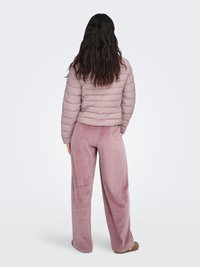 Doudoune rose pâle avec un design matelassé. Associée à un pantalon large et douillet de la même teinte rose, pour un look confortable.