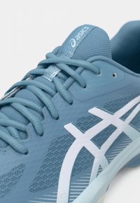 Αθλητικό παπούτσι ανοιχτού γαλάζιου χρώματος με υλικό από δίχτυ, υφηλώσεις, λευκή επωνυμία και έξι ομοιόχρωμες οπές για κορδόνια.