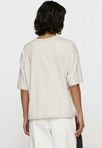 Jasno beżowy t-shirt z krótkim rękawem o lekko luźnym kroju, z okrągłym dekoltem i miękkim, teksturowanym bawełnianym materiałem.