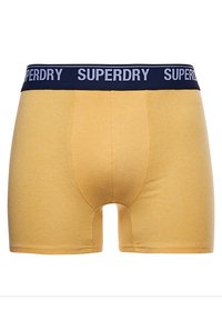 Geel katoenen boxershorts met een marineblauwe elastische tailleband, met de merknaam "SUPERDRY" in het wit. Aansluitend ontwerp, soepele textuur.