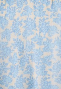 Tela ligera con un estampado floral en tonos azules suaves sobre un fondo beige claro, con una textura plisada en toda su superficie.