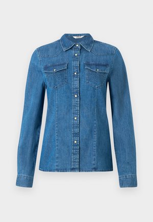 Chemise en denim de couleur bleue moyenne, dotée d'une fermeture à boutons sur le devant, de deux poches poitrine et d'un col. Texture lisse avec des coutures décoratives.