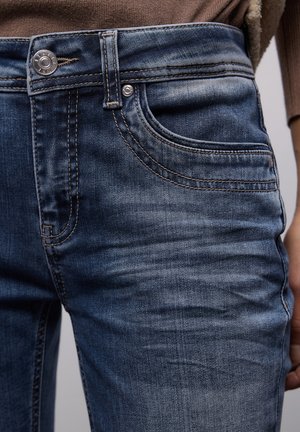 Jeans en denim bleu foncé avec une finition délavée, dotés d'une poche avant, d'un bouton en métal, et de coutures discrètes à la ceinture et aux coutures.