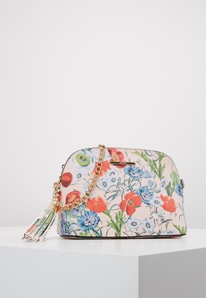 Torebka w kwiatowy wzór z czerwonymi, niebieskimi i białymi kwiatami, złotym łańcuszkiem oraz pasującym chwostem na białym postumencie.