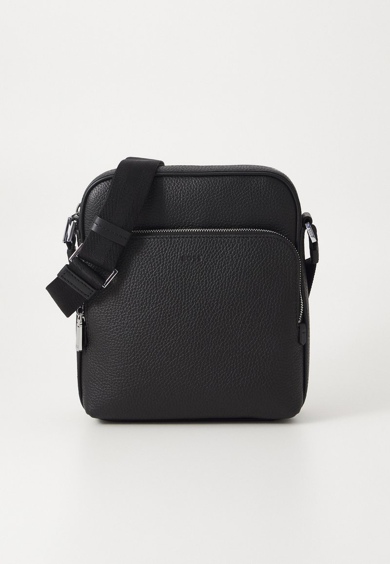 Svart läder crossbody-väska med en texturerad yta, utrustad med en framficka med dragkedja, justerbar rem och metalliska detaljaccent.