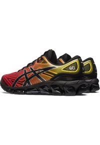 Scarpe sportive con un design a gradiente rosso, arancione e giallo. Presentano dettagli neri, tomaia in rete e una suola imbottita nera con inserti in gel.