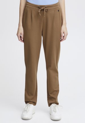 Pantaloni da tuta marroni, svasati, realizzati in un tessuto morbido con vita a coulisse, dotati di pieghe laterali e un piccolo logo accentato vicino alla tasca.