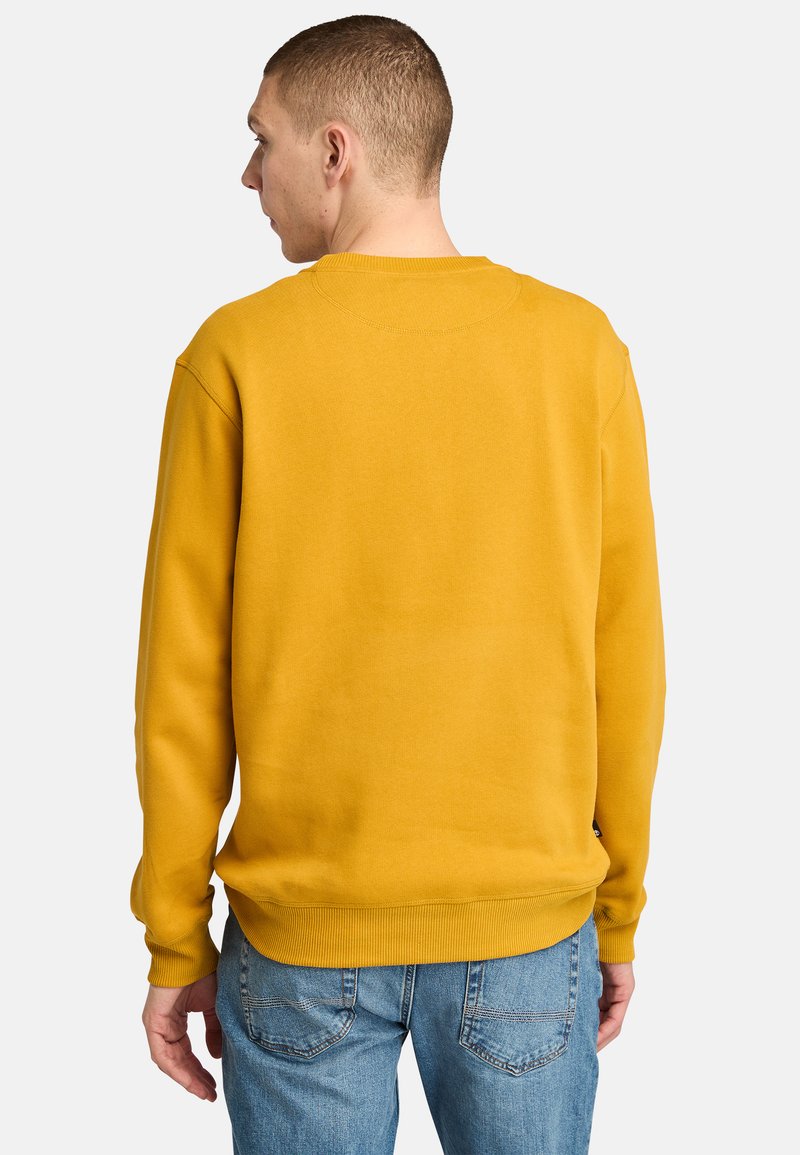 Felpa gialla con collo a giro, polsini e orlo a costine; mostrata dal retro, abbinata a jeans azzurri chiari. Tessuto morbido.