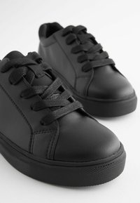 Baskets en cuir noir avec des bouts ronds, semelles en caoutchouc texturé et lacets plats. Fini lisse avec de subtils détails de couture.