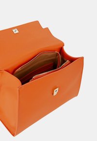 Sac à main en cuir orange, présentant une forme structurée, une ouverture sur le dessus, des poches zippées à l'intérieur, et un petit détail en métal doré.