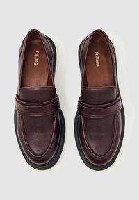 Tume burgundi nahkast loafers, millel on siledad pinnad, ümar varvas ja kontrastne must kummitald. Ees on õmmeldud riba detail.