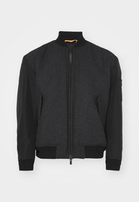 Veste bomber noire avec un panneau avant texturé, des manches noires lisses, une fermeture éclair, et des poignets et un ourlet côtelés. Accent de col intérieur orange vif.
