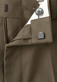 Olivgrüner Stoff mit glatter Textur verfügt über einen Reißverschluss und einen eleganten Knopfverschluss. Flache Nähte akzentuieren den Saum und den Bund.