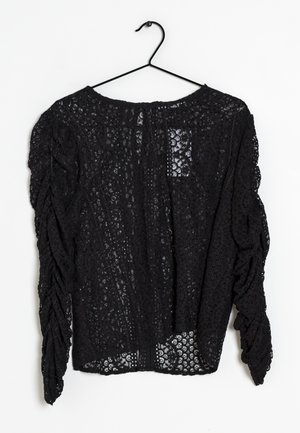 Musta pitsitoppi roikkumassa koukussa, jossa on teksturoitu kukkakuosi, rypytetyt hihat ja pyöreä pääntie.