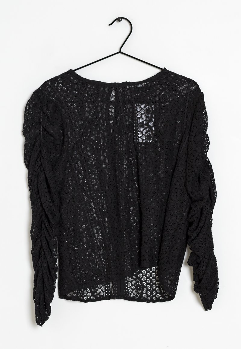 Top in pizzo nero appeso a un gancio, con un motivo floreale a rilievo, maniche arricciate e scollo rotondo.