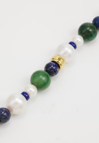 Perlenkette mit grünen, blauen und weißen Perlen, akzentuiert mit Gold. Runde Perlen in verschiedenen Größen schaffen ein strukturiertes, farbenfrohes Design.