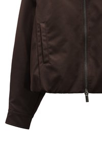 Brązowa, zapinana kurtka o gładkiej fakturze. Posiada boczną kieszeń oraz dopasowane mankiety, zaprojektowana w prostym, nowoczesnym stylu.