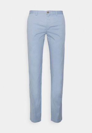 Jasnoniebieskie męskie chinosy o wąskim kroju, z szlufkami na pasek, zapinane z przodu na guzik i zamek, pokazane z przodu na jednolitym tle.