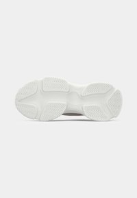 Sole di sneakers bianche con profondi motivi a zigzag sulla parte del tallone, del mesopiede e delle punte per trazione e stabilità.