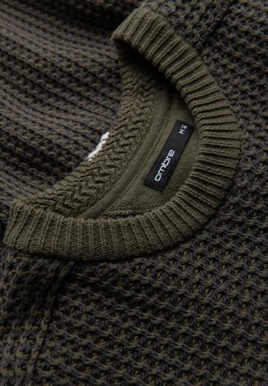 Tumman oliivinvihreä neulepaita, jossa on teksturoitu vohvelikuvio ja ribbineulekaulus. Tunnuksessa lukee "ombre", koko M.