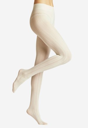 Benen gekruist in de lucht, gekleed in crèmekleurige, gestructureerde panty's met patroon en hoge taille, tegen een effen achtergrond.