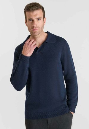 Pull en maille bleu marine avec un col plat, des manches longues et des poignets côtelés. Texture douce et design ajusté avec une couleur unie sur l'ensemble.