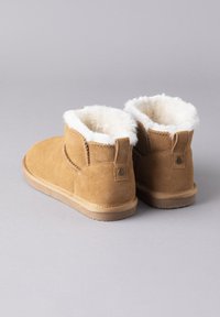 Brown suede ankle boots with a soft white faux fur lining, featuring a flat rubber sole and a back loop for easy wear.