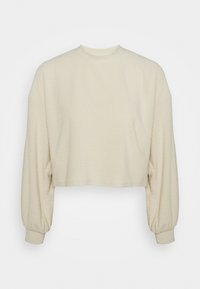 Top corto de color crema con un patrón texturizado tipo waffle. Cuenta con mangas largas y voluminosas y un escote redondo.