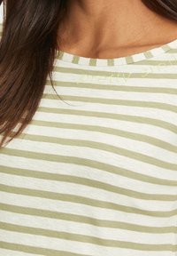 Lätt randig t-shirt med växelvis vita och olivgröna horisontella ränder, med texten "pretty smile" i ljusgrön stygn.