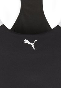 Top sportiv negru cu spate decupat, având un logo alb Puma pe față și un material neted, texturat.