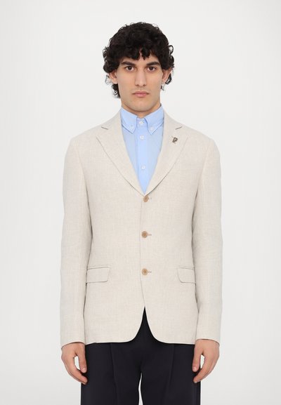 Lys beige linned blazer med udskårne lapeller, to frontlommer og træknapper, parret med en blå skjorte med krave under.