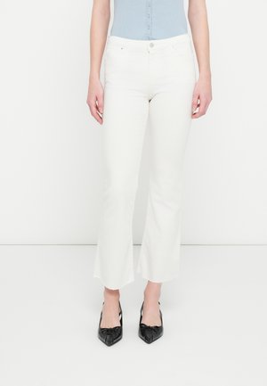 Jeans bianchi a zampa d'elefante con vita media, dotati di tasche frontali e una texture liscia. Indossati con décolleté nere con punta a stiletto.