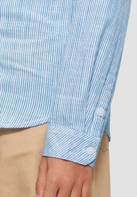 Blauw-witte gestreepte shirt met een knoopmanchet, van soepel katoen en een getailleerde pasvorm. De strepen zijn gelijkmatig verdeeld en verticaal.