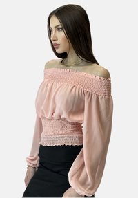 Off-the-shoulder lyserød bluse lavet af letvægtsstof, med smocket talje og puffede ærmer med rynkede detaljer.