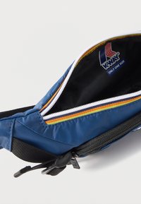 Μπλε υφασμάτινη τσάντα μέσης με λευκό φερμουάρ, πολύχρωμη διακόσμηση, μαύρο λουρί και ετικέτα "K-Way Only One Size" μέσα στο κύριο διαμέρισμα.