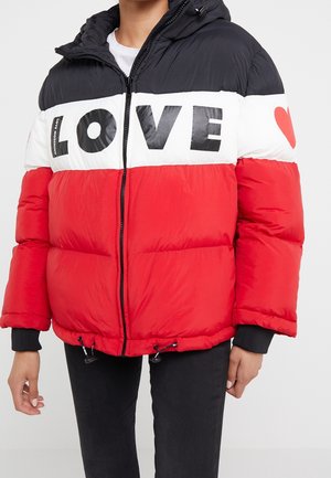 Persoon draagt een zwart-wit-rode gewatteerde jas met de tekst "LOVE" over de borst en een rood hart op de linker mouw.