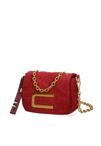 Sac à épaule en daim rouge avec une bandoulière en chaîne dorée, un corps texturé et un logo doré bien visible à l'avant. La bandoulière latérale a une étiquette de la marque.