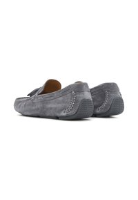 Mocasines de ante gris con costuras decorativas y una suela de goma flexible. Diseño de parte trasera abierta, textura suave y acentos sutiles en el talón.