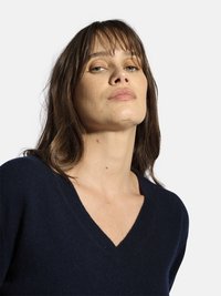 Granatowy sweter v-neck wykonany z miękkiego materiału o luźnym kroju. Posiada podwójne wykończenie w okolicy dekoltu i mankietów.