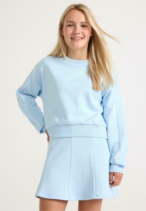 Sweatshirt bleu clair à manches longues avec des bordures blanches, associé à une jupe plissée assortie de la même couleur, le tout en tissu doux.