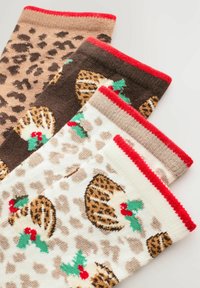 Three pairs of festive patterned socks with leopard spots and Christmas pudding designs, each with a red cuff, laid overlapping on white.