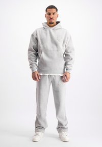 Grijze hoodie en bijpassende sweatpants van zacht materiaal. Kenmerken een voorzak en geborduurde ontwerpelementen. Klassieke relaxte pasvorm.