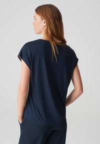 Top blu navy a maniche corte con vestibilità morbida, texture soffice, scollatura rotonda e orlo leggermente curvo, realizzato in tessuto leggero.