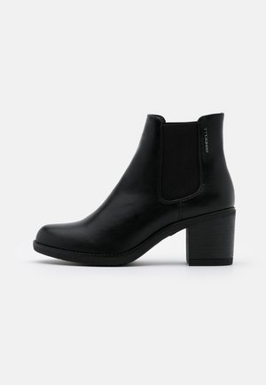 Bota negra de cuero hasta el tobillo con tacón bajo y grueso, panel elástico lateral y acabado liso.
