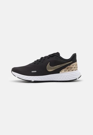 Sort løbesko med hvid sål, gyldent Nike-swoosh på siden og flere små sorte swooshes på den gyldne hælpanel.