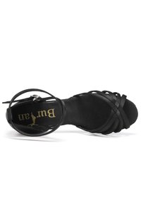 Black strappy high heel shoe featuring a textured sole, delicate straps, and a zip closure at the back, with branding on the insole.