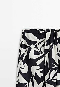 Zwart-wit stoffen met bloemenpatroon en een textuurlijke uitstraling, met een geplooide tailleband en een discrete rits aan de zijkant.