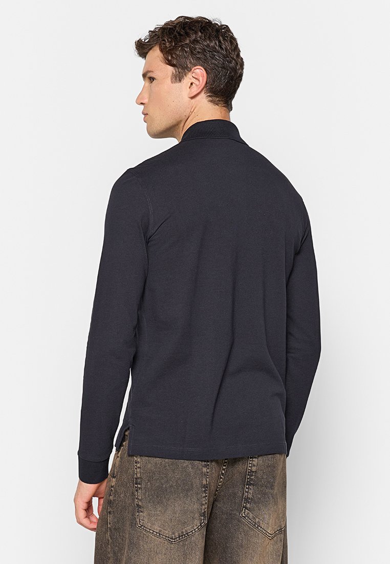 Navy langemouwen polo shirt van gladde katoen, met een geribde kraag en zijsplitten, gecombineerd met vervaagde bruine cargobroek.