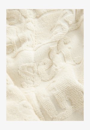 Gestructureerde crèmekleurige stof met een zachte, pluizige oppervlak. Heeft verhoogde patronen die diepte en visuele interesse bieden. Lichtelijk gerimpelde uitstraling.