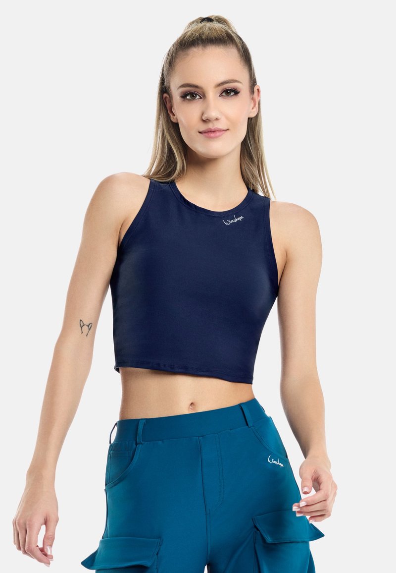 Top corto navy blue in materiale liscio con scollatura rotonda e dettaglio del logo. Pantaloni cargo teal con tasche completano l'outfit.